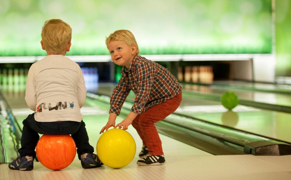 twee kinderen die op een bowlingbal zitten